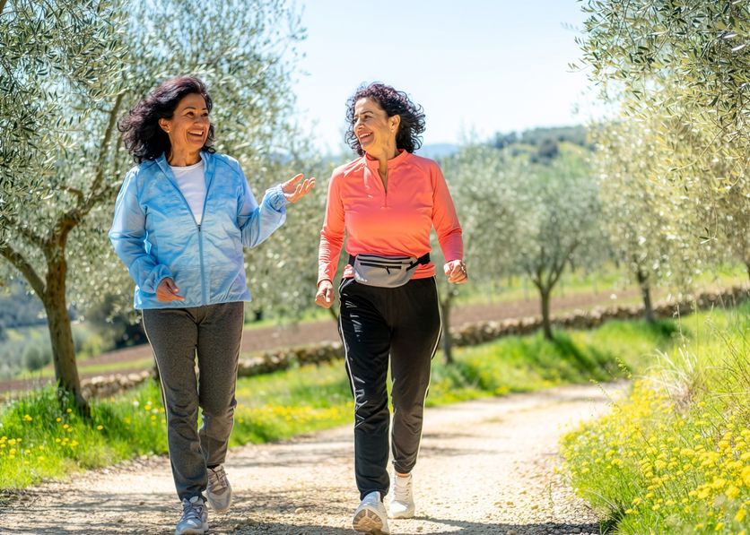 Due amiche camminano a passo moderato tra gli ulivi